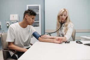 Médica afere a pressão arterial de um paciente durante consulta em consultório clínico