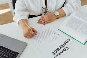 Profissional assina contrato de trabalho sobre a mesa, ao lado de um livro de direito