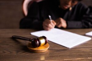 Magistrada assina uma decisão ao lado do martelo sobre a mesa do tribunal