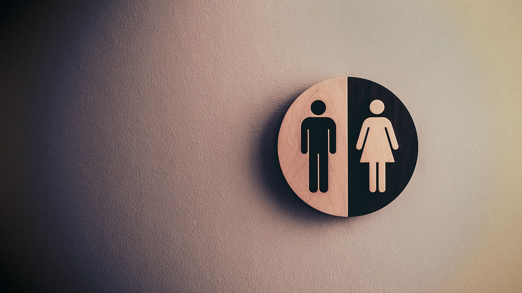 Placa redonda de banheiro masculino e feminino fixada na parede de um ambiente de trabalho