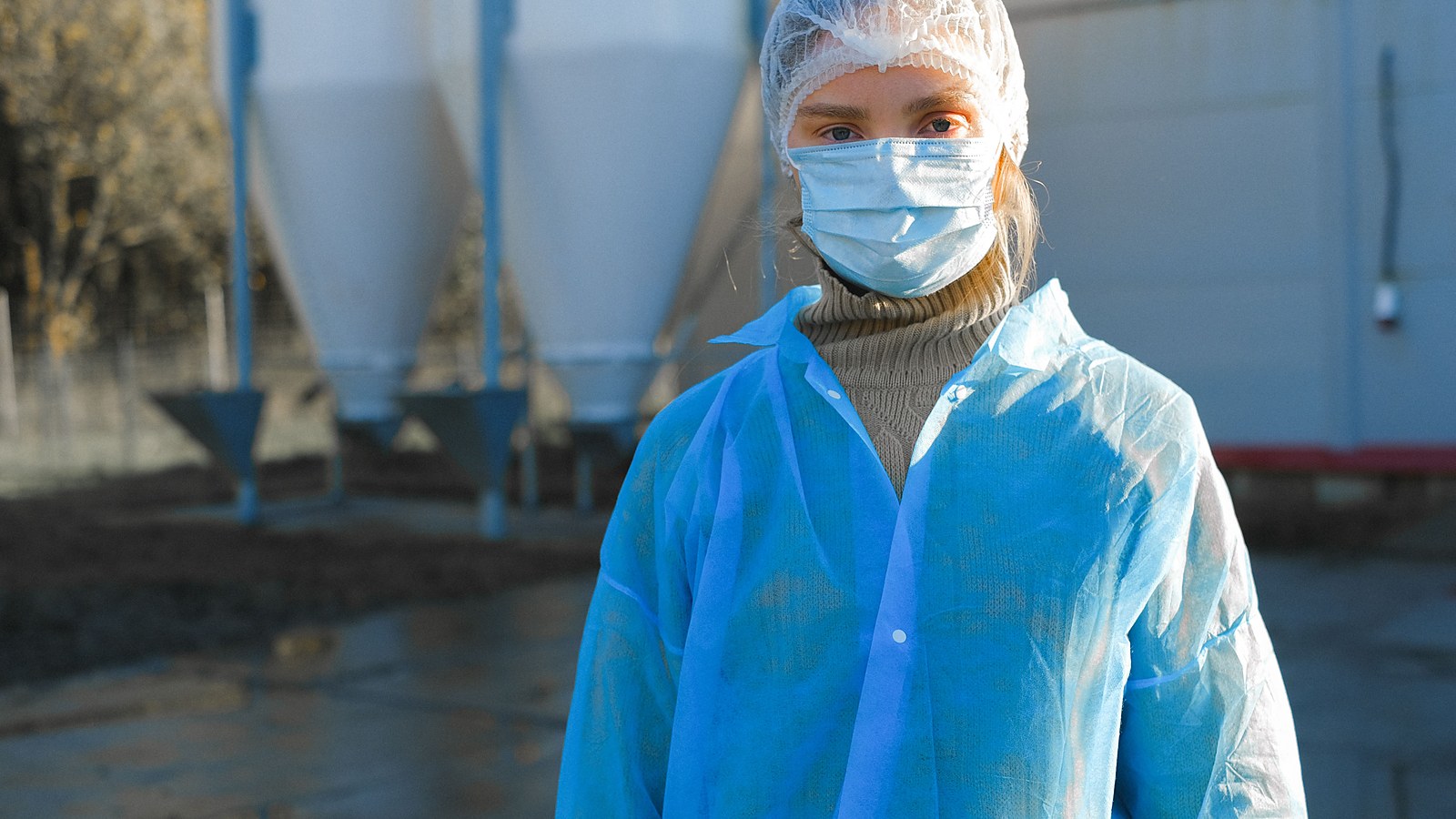 Trabalhadora de frigorifico paramentada com touca descartavel, mascara e avental na area industrial