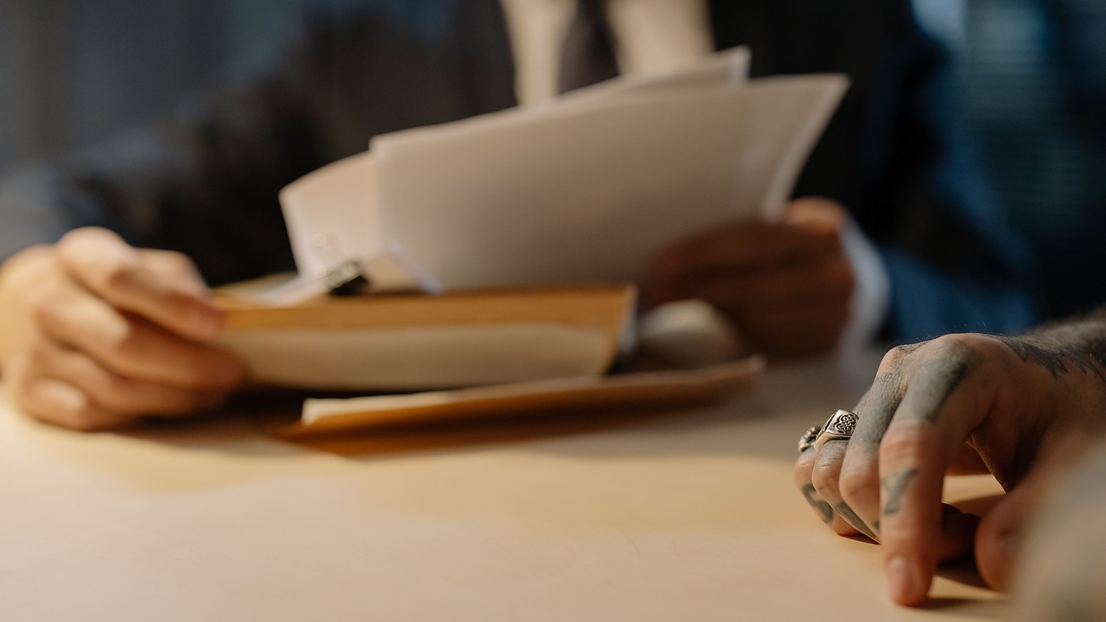 Maos de advogados folheando documentos em papel sobre a mesa durante analise de um processo