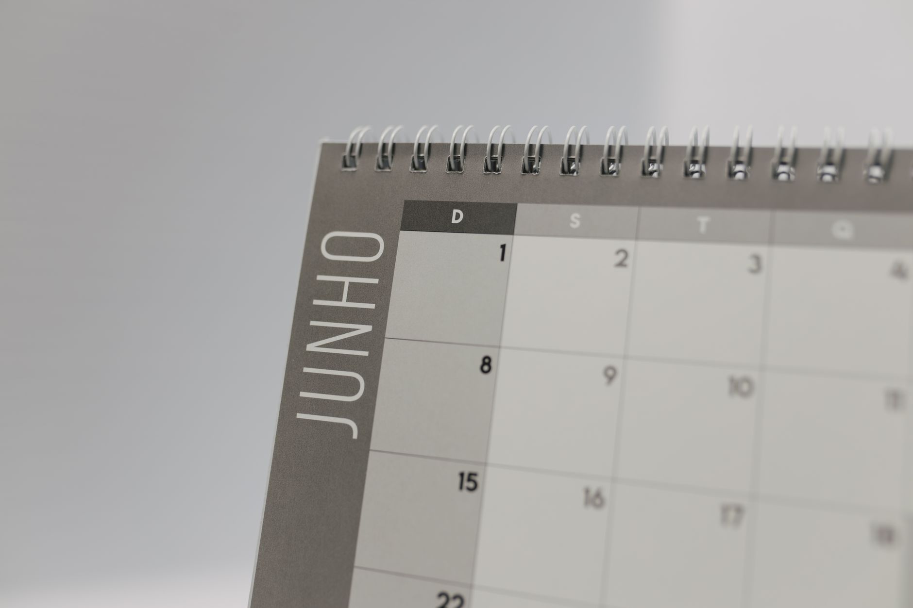 Calendário de mês aberto sobre a mesa com três semanas destacadas e um domingo circulado em cada bloco, ao lado de uma escala de trabalho impressa, representando o repouso semanal que deve coincidir com o domingo a cada três semanas