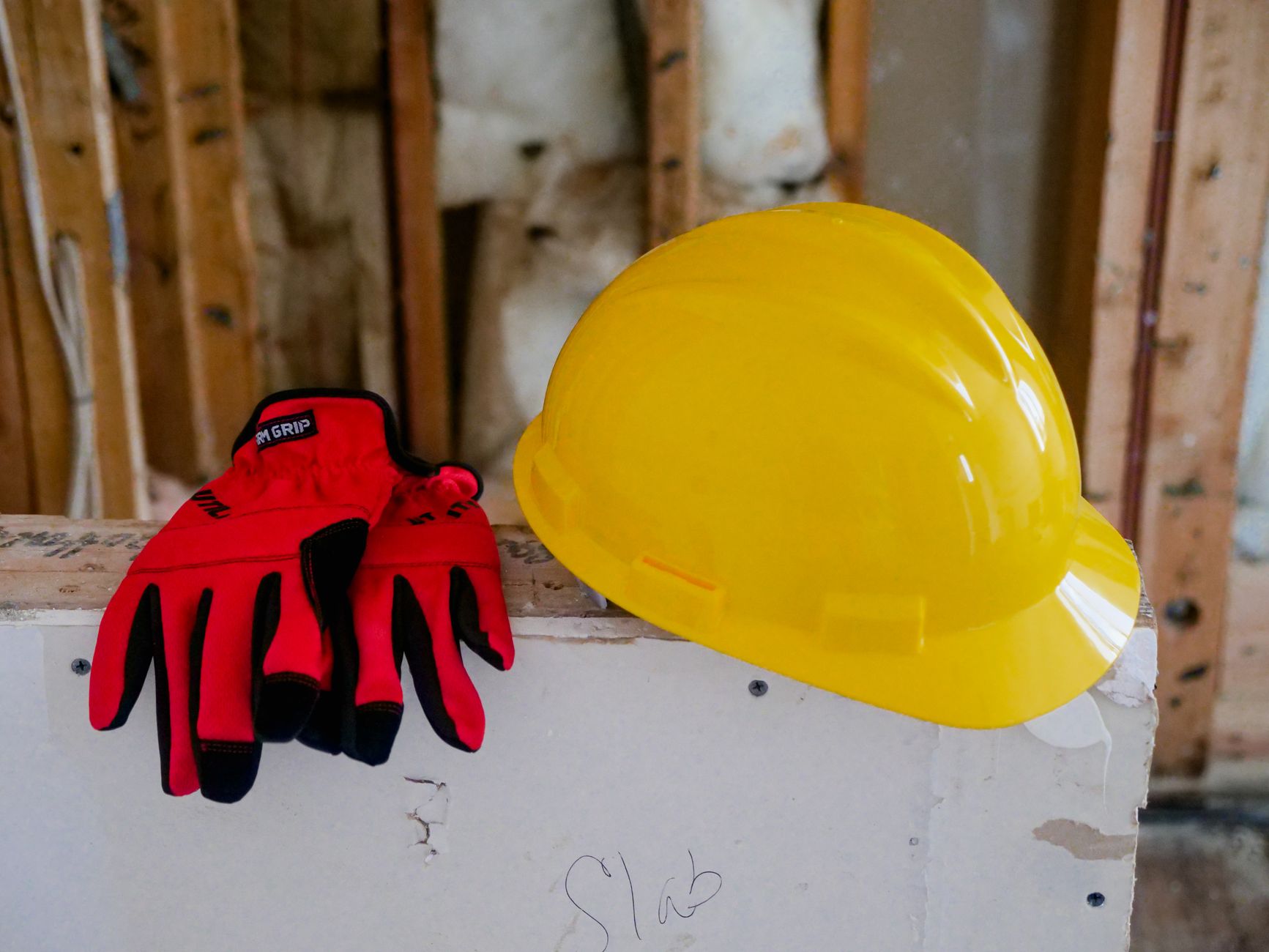Capacete de segurança e luvas de proteção sobre uma superfície, equipamentos de proteção individual, sem pessoas.