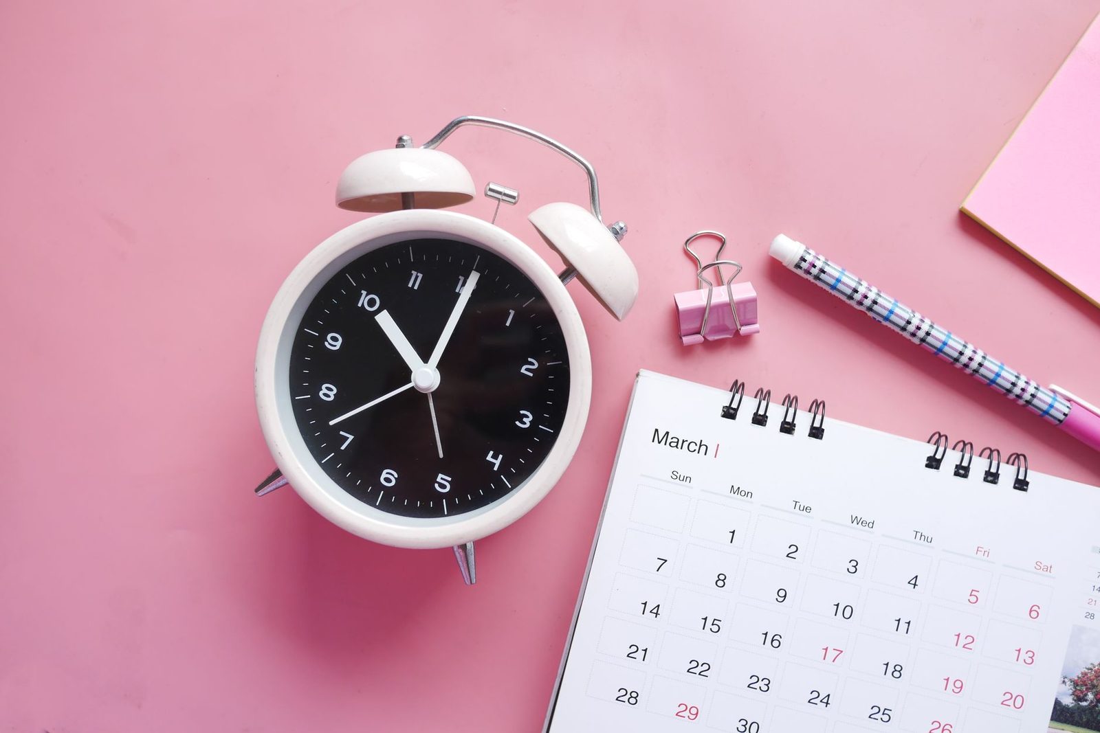 Despertador ao lado de calendario, remetendo as jornadas e aos periodos de descanso