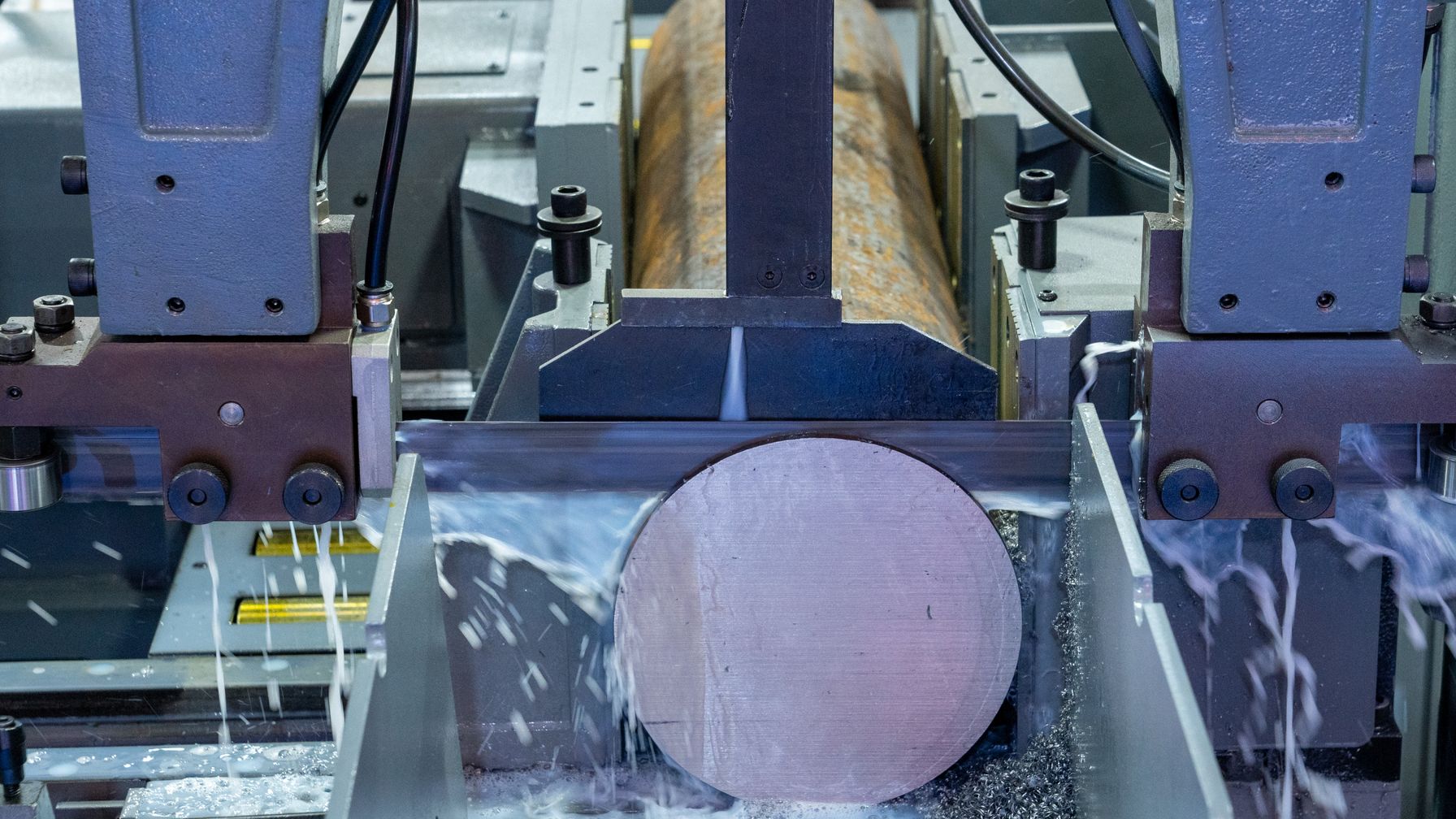 Máquina industrial de corte serrando uma barra de metal, ilustrando os requisitos da NR-12 e da NR-36 para máquinas de corte no abate